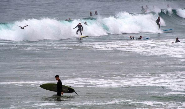 Surfers take to the water just north of the Newport Pier in Newport Beach early Saturday morning, January 15, 2022, after a tsunami advisory was issue