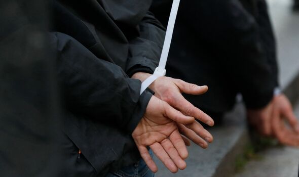 French anti-riot policemen detain two men with their hands tied on the Champs Elysees